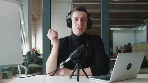 Man Talking Into Microphone Near Laptop on Desk