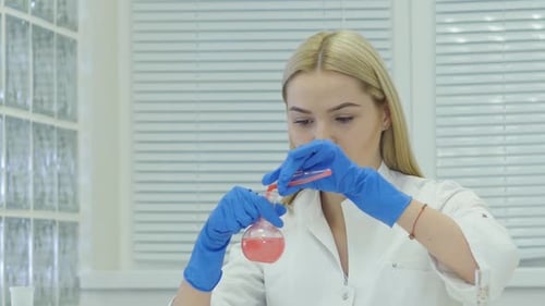 Scientist mixing chemicals in laboratory with flask