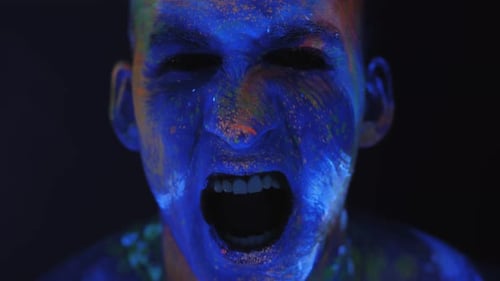 Portrait of Young Man in UV Paint, He Screams with His Mouth Wide Open.