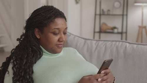 Young Woman Lying on Sofa and Receiving Telephone Call