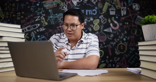 Young Adult Studying At Desk Using Laptop