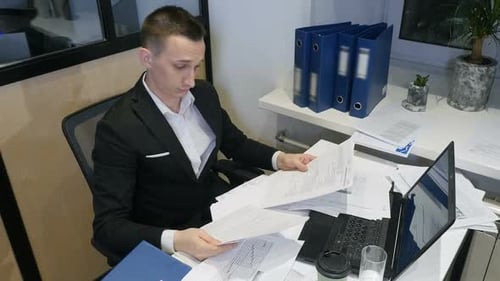 Young Businessman At Work. A Successful Manager Working With Papers and Laptop In Office.