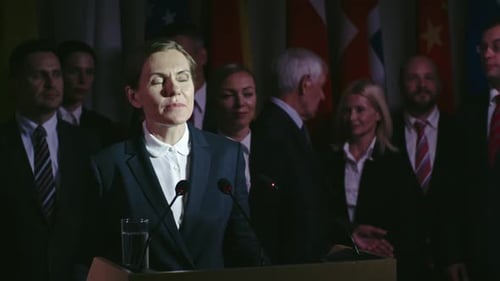 Woman Giving Speech at Podium with Flags