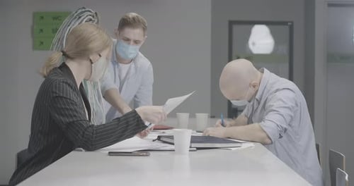 Group of Young Colleagues in Covid Face Masks Sitting at the Table in Office and Talking