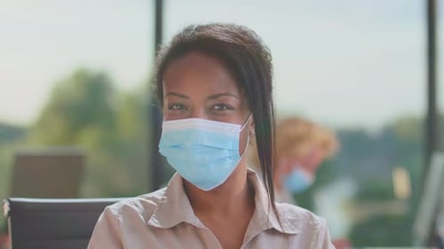 Woman with Mask Looking at Camera in Office