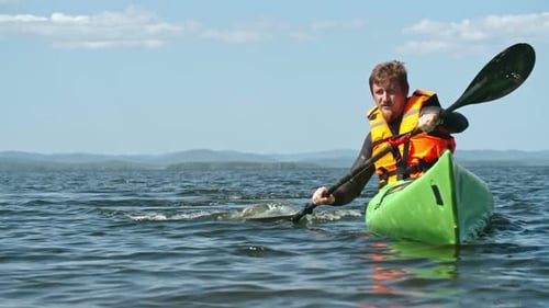Man Paddles a Kayak on a Lake