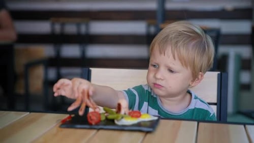 Blond Child Looks at Plate of Sausages and Egg