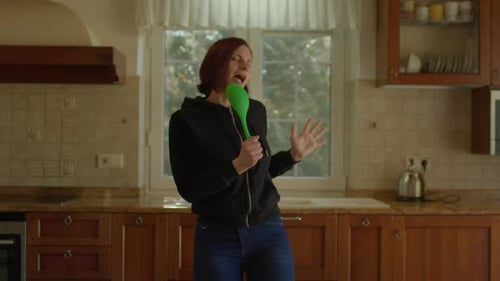 Woman Singing and Dancing in Kitchen with Spoon