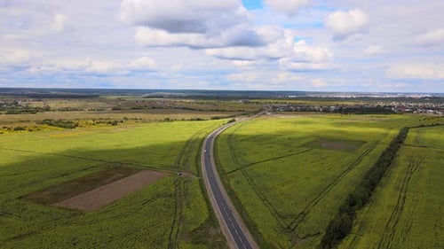 Aerial View of Intercity Road Between Green Agricultural Fields with Fast Driving Cars