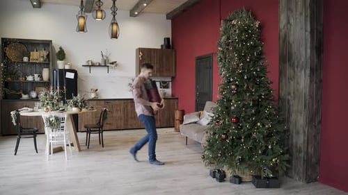 Man Arranging Christmas Presents Under Decorated Tree