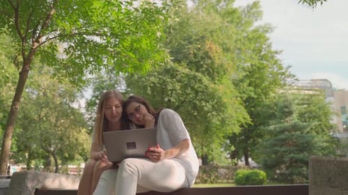 Jeune femme aidant sa vieille mère retraitée sur un ordinateur portable assise dans un parc. Concept d'inclusion fondée sur l'âge