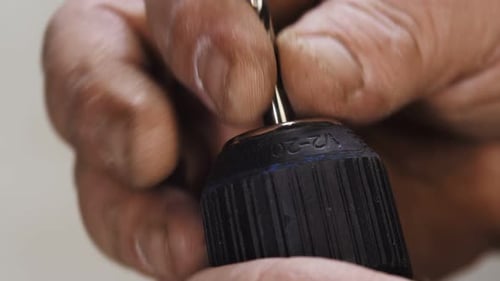 Hands Inserting Drill Bit Into Power Drill