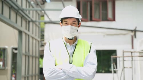 Construction Worker Puts on Face Mask and Folds Arms