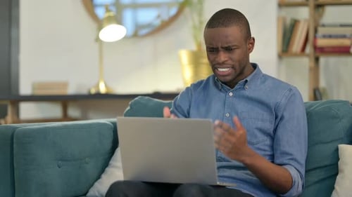 Man Upset While Using Laptop on Couch