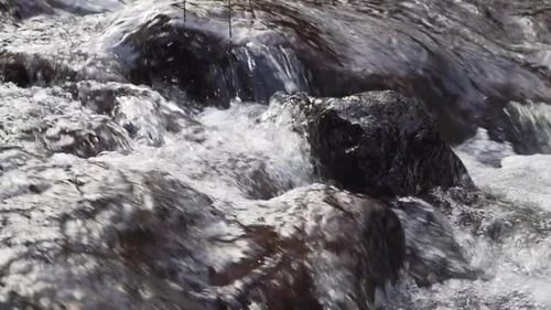 Wasser fließt in Zeitlupe über Felsen.