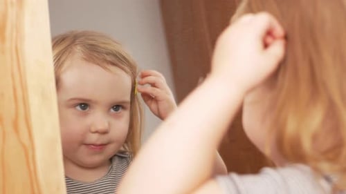 Kleines süßes Mädchen zeigt sich in der Nähe von Spiegelposen untersucht sich windet sich