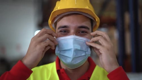 Young man working in warehouse while wearing face mask during corona virus pandemic