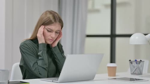 Young Woman Experiencing Headache at Her Desk
