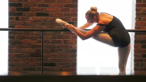 Ballerina Stretching Leg in Dance Studio