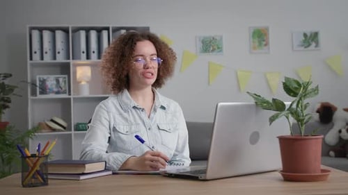 Smiling Woman on Video Call Taking Notes