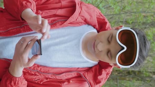 Adult with Phone Wearing Ski Goggles Outdoors