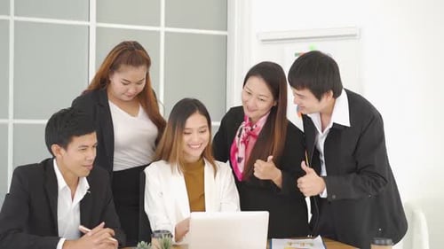 Cheerful Colleagues Collaborate on Laptop in Modern Office