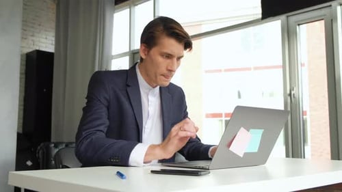 Man With Laptop Finishing Work At Office. Panning shot of businessman finishing working on laptop