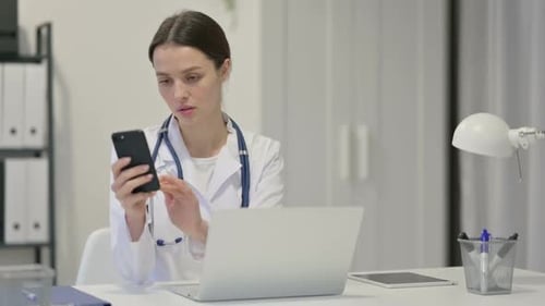 Female Doctor Using Phone at Office Desk