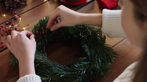 Woman Decorating Christmas Wreath with Berries