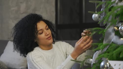 Woman Decorates Christmas Tree with Silver Ornaments