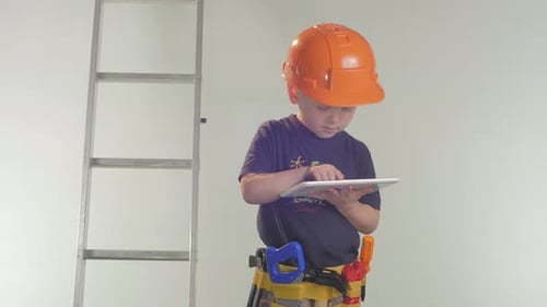 Child Wearing Hard Hat Uses Tablet Indoors