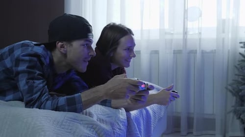 Young Adults Playing Video Games on Bed
