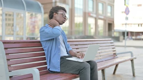 Young Adult Using Laptop on Bench Outdoors