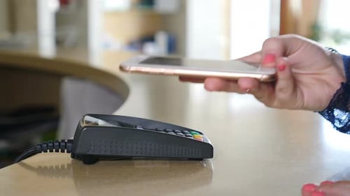 Female Paying with Smart Phone Using NFC Technology. Close-up. Contactless Payment with Smartphone