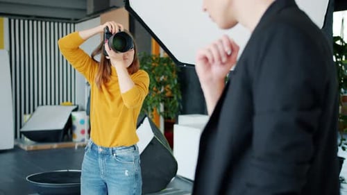 Pretty Woman Photographer Taking Pictures of Man Model Posing in Studio
