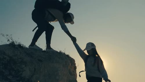 Girl Helps Her Friend Climb Up the Last Section of Mountain
