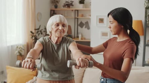 Senior Woman Doing Dumbbell Exercises With Young Adult