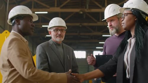 Female Factory Engineer Shaking Hands and Speaking with Colleagues