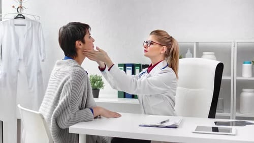 Doctor Examines Patient's Neck in Bright Office