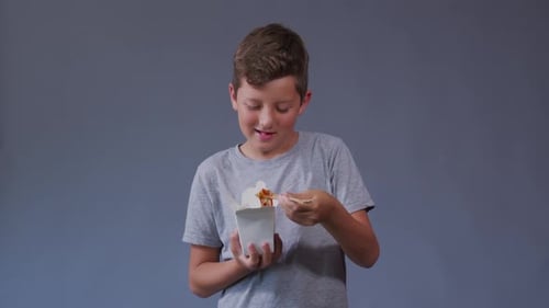Boy Enjoys Noodles from a Takeout Container