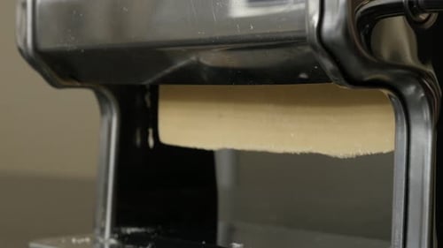 Flattened dough in pasta machine close-up 4K 2160p 30fps UltraHD footage - Italian lasagna sheets m
