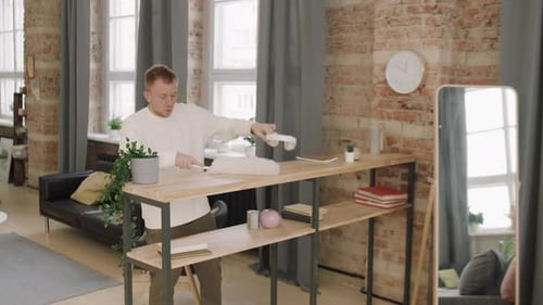 Young Man Dusting Shelves in Modern Apartment