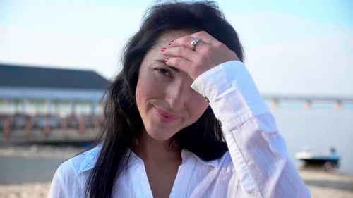 Woman Smiling and Touching Hair on the Beach