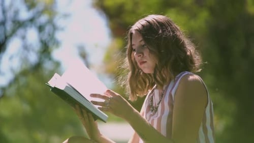 Woman Reads Book Outdoors in Green Park Setting