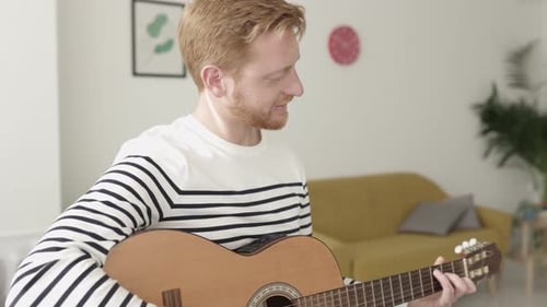 Man Plays Guitar at Home in Living Room