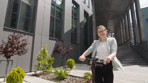 Young Woman Rides Electric Scooter in the City