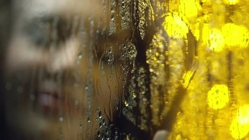 Woman Draws on Rain Covered Window at Night