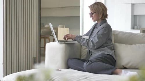 Woman Working on Laptop From Couch at Home