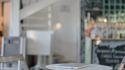 Young Adult Opening Laptop at Cafe Table