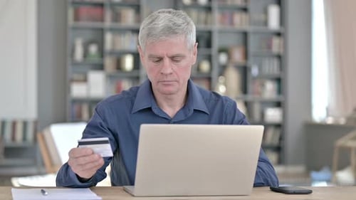 Serious Man Making Online Payment By Credit Card on Laptop in Office